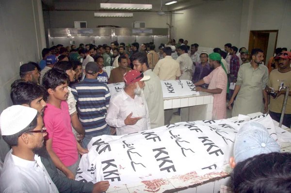 As pessoas se reúnem perto dos mortos corpóreos de vítimas de fuzilamento no Hospital Abbasi Shaheed em Karachi — Fotografia de Stock