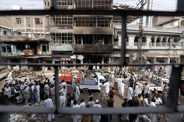 Personas y rescata a funcionarios ocupados en trabajos de rescate en el sitio de la explosión de la bomba de ayer en la estación de policía de Khan Raziq en el área del bazar Qissa Khawani —  Fotos de Stock