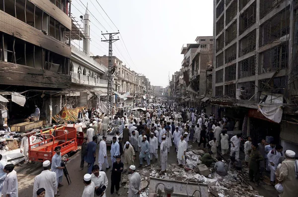 Pessoas e resgata funcionários ocupados em trabalhos de resgate no local da explosão de ontem bomba na Delegacia de Polícia Khan Raziq em Qissa Khawani área bazar de Peshawar — Fotografia de Stock