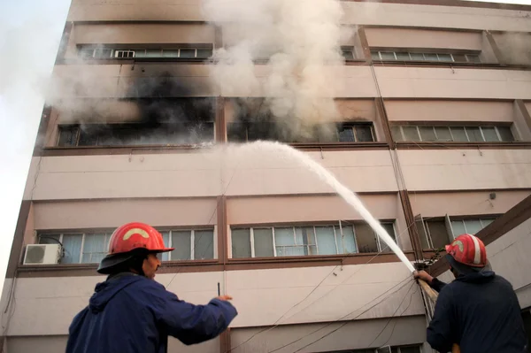 忙しいの消防士は火を消す燃えさかる火電気による事件が勃発した後の建物上の優しい資金の建物で短絡 ロイヤリティフリーのストック画像