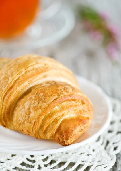 Croissant mit einer Tasse Tee — Stockfoto