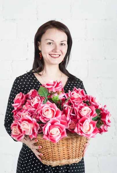 Mooie vrouw met rode bloemen in de mand — Stockfoto