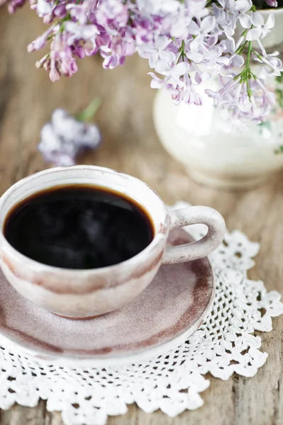 Kopje koffie en lila bloemen boeket — Stockfoto