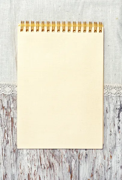 Papír notebook és ágynemű szövet a régi, fából készült háttér — Stock Fotó