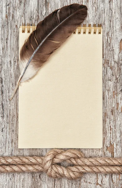 Ship rope, feather, spiral notebook and wood background — Stock Photo, Image