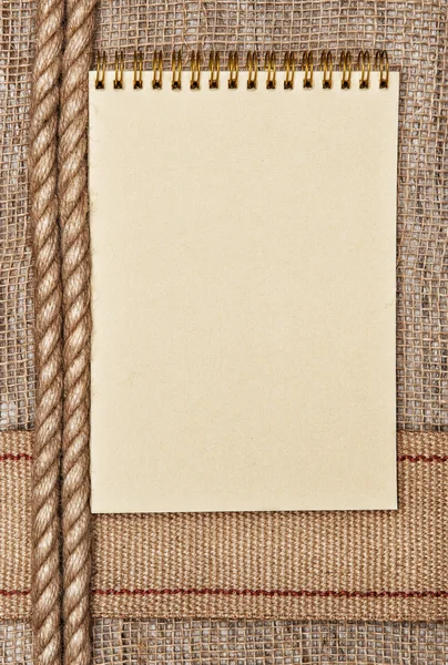 Burlap background with sacking ribbon, rope and notebook — Stock Photo, Image