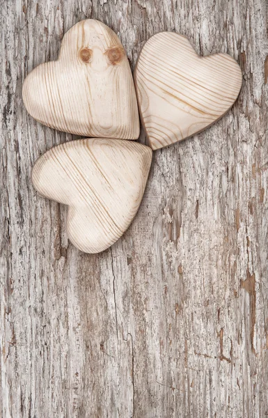 Drie houten hartjes op het oude hout — Stockfoto