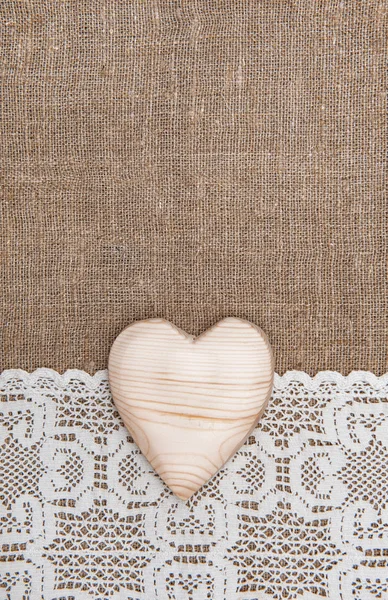 Бурлап фон с кружевной тканью и деревянным сердцем — стоковое фото