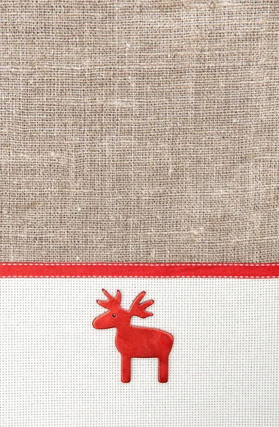 Karácsonyi kártya vászon, piros szalag és szarvas a zsákvászon — Stock Fotó