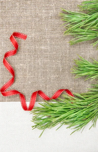 Christmas card with canvas, fir branch and ribbon on burlap — Stock Photo, Image