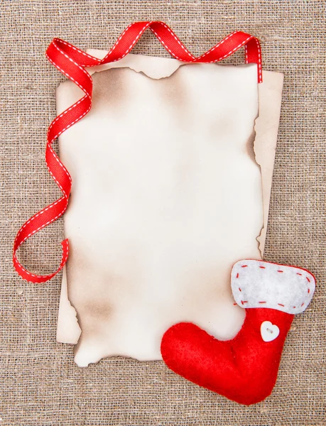 Christmas card with aged paper, sock and ribbon on burlap — Stock Photo, Image