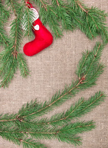 Christmas decoration with fir branches and red sock on burlap — Stock Photo, Image