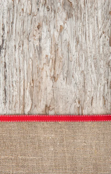 Old wood bordered by burlap and red ribbon — Stock Photo, Image