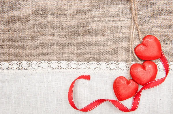 Ξύλινα καρδιές, κορδέλα και λινό ύφασμα σε λινάτσα — Φωτογραφία Αρχείου