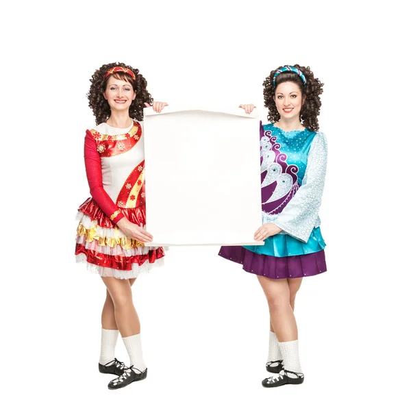 Две молодые женщины в ирландских танцевальных платьях с пустой бумагой — стоковое фото
