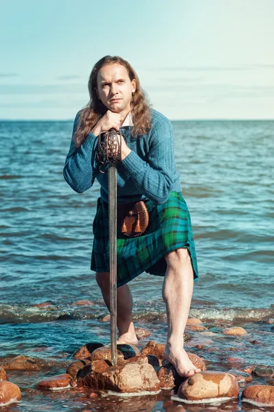 Scottish man with sword at the sea — Stock Photo, Image