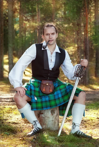 Handsome scottish man with sword and pipe — Stock Photo, Image