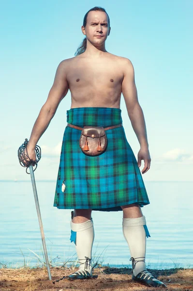 Hombre escocés con espada cerca del mar — Foto de Stock