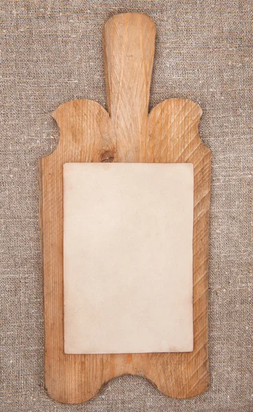 Tablero de cocina de madera vieja con papel envejecido en la arpillera — Foto de Stock