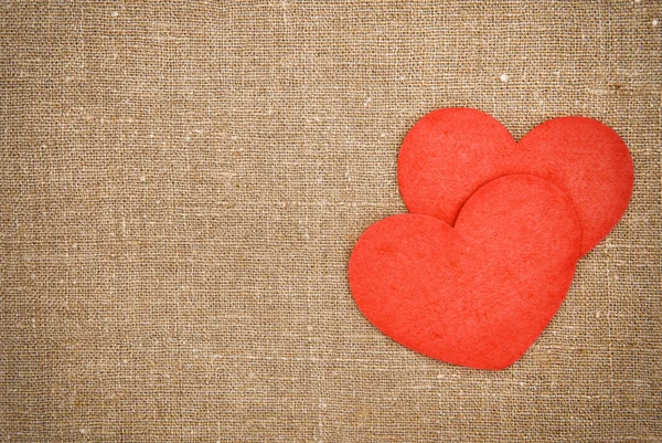 Красные сердечки на мешковине — стоковое фото