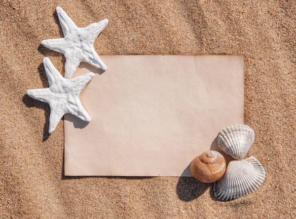 Sheet of paper and seashells on the sand — Stock Photo, Image