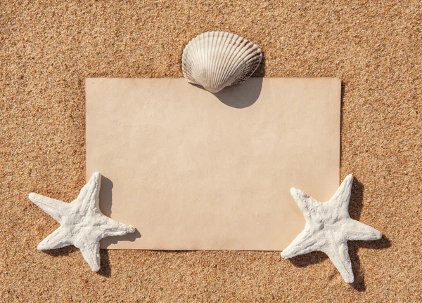 Pappersark och snäckskal på sanden — Stockfoto