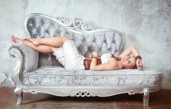 Bella donna in corsetto e pantaloni sul divano — Foto Stock