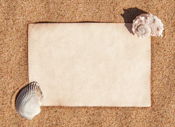 Hoja de papel y conchas marinas sobre la arena — Foto de Stock
