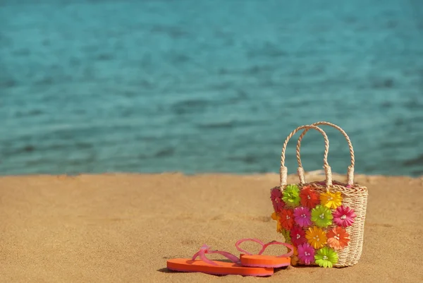 Hausschuhe mit Korbtasche am Strand — Stockfoto