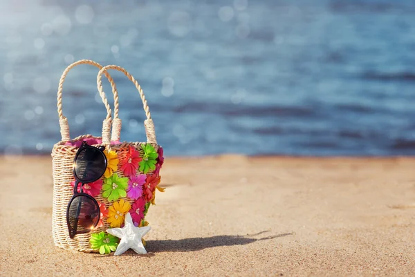 Bolsa de vime e óculos de sol na praia — Fotografia de Stock