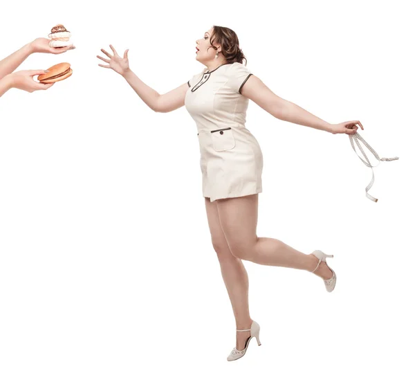 Além de tamanho mulher desejo de junk food com centímetro nas mãos — Fotografia de Stock