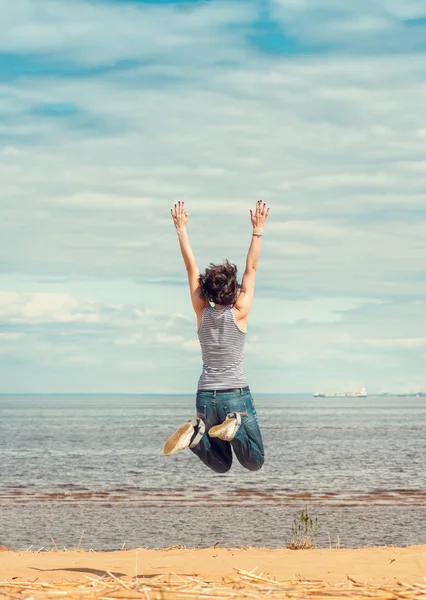 Femme heureuse sautant sur la plage — Photo
