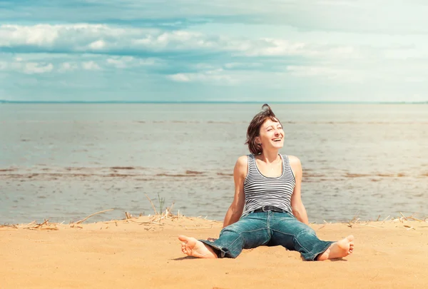 Glückliche Frau sitzt am Strand — Stockfoto