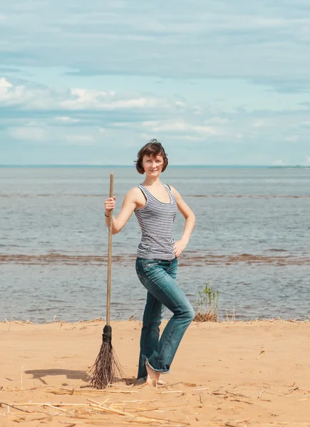 Kvinna med kvast på stranden — Stockfoto