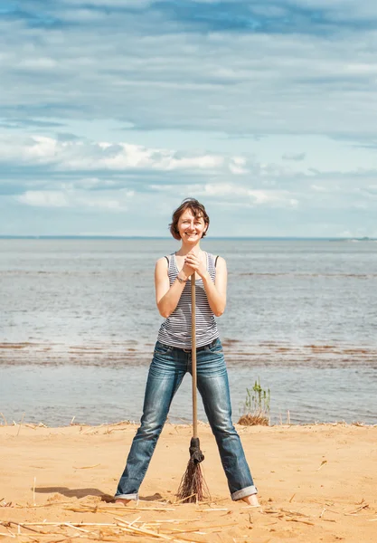 Kvinna med kvast på stranden — Stockfoto