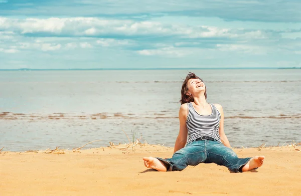 Skrattar kvinna som sitter på stranden — Stockfoto