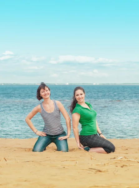 Duas mulheres felizes sentadas na praia — Fotografia de Stock