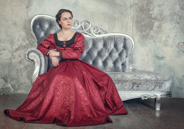 Hermosa mujer en vestido medieval en el sofá — Foto de Stock