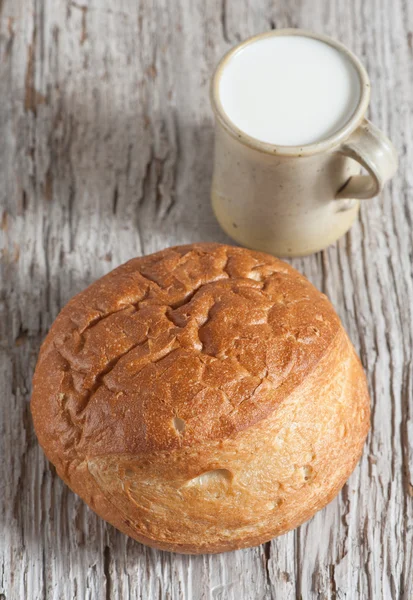 Hembakat bröd och mjölk i trä styrelsen — Stockfoto