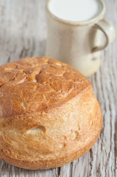 Hembakat bröd och mjölk i trä styrelsen — Stockfoto