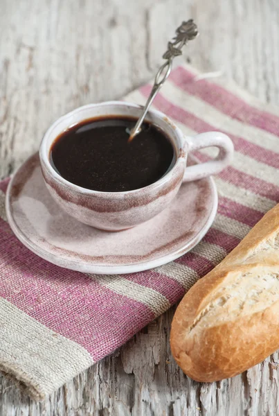 Baguete e xícara de café na tábua de madeira — Fotografia de Stock