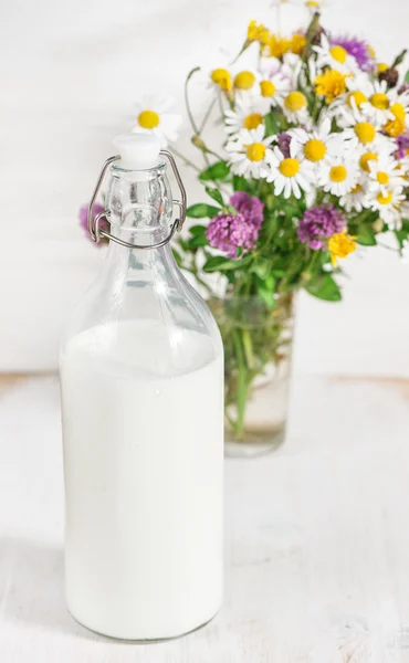 Leche fresca en botella pasada de moda y flores silvestres —  Fotos de Stock