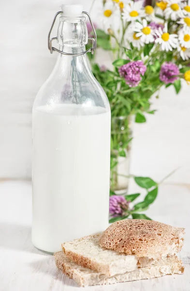 นมสดในขวดเก่าและขนมปังโฮมเมด — ภาพถ่ายสต็อก
