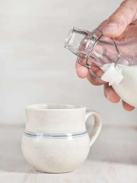Homem mão derramando leite de garrafa — Fotografia de Stock