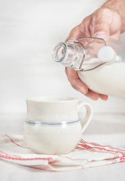 Man hand pouring milk from bottle — Stock Photo, Image