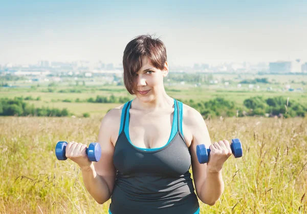 Beautiful plus size woman exercising with dumbbells — Stock Photo, Image