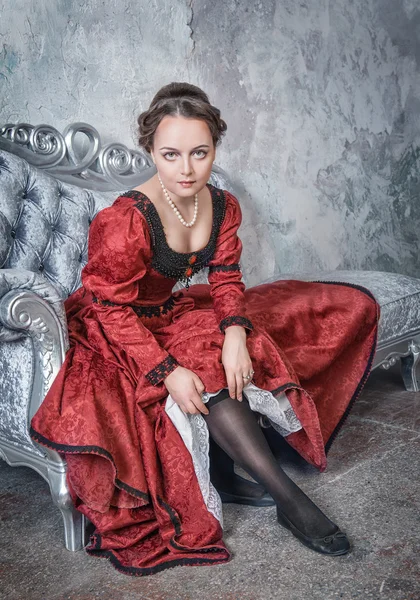 Hermosa mujer en vestido medieval poniendo medias — Foto de Stock