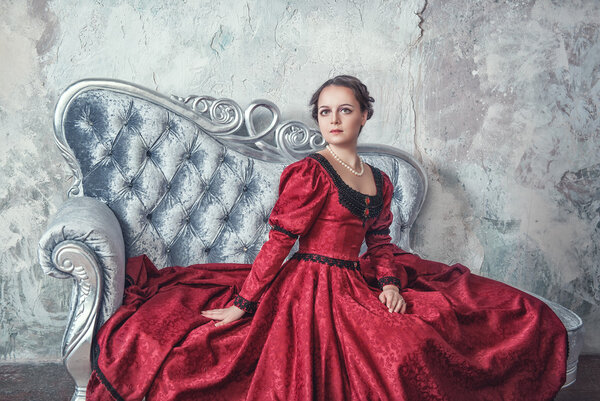 Beautiful woman in medieval dress on the sofa