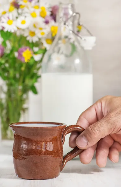 Man hand holding ceramic mug with milk — Stock Photo, Image