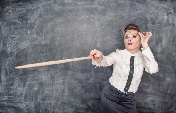 Strict teacher showing on something by wooden pointer — Stock Photo, Image